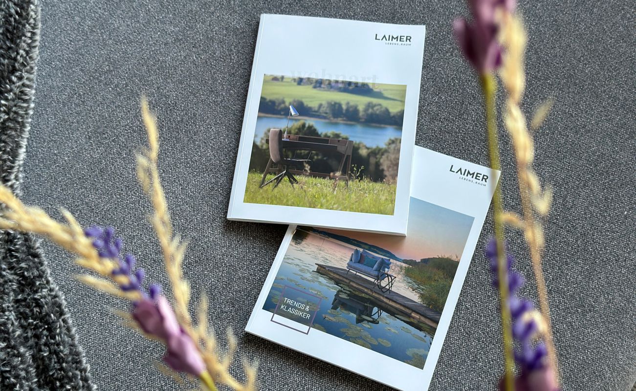 Zwei Kataloge von Laimer liegen auf einem grauen Untergrund, umgeben von Lavendel und einer dekorativen Textur.